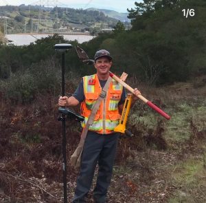 Crew Chief Miles Wadsworth stands confidently at a worksite in Watsonville, surrounded by construction equipment and an active project environment. The image emphasizes leadership, professionalism, and dedication to achieving project goals.