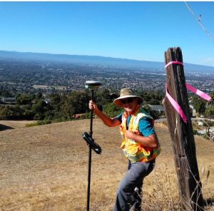 Crew Chief Miles Wadsworth overlooks Pajaro Valley from an elevated vantage point, framed by rolling hills and a vast open landscape. The image conveys a sense of strategic vision, leadership, and connection to the natural environment.