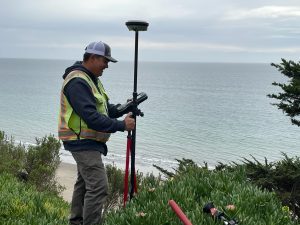 Crew Chief Jared Nielsen stands in Moss Landing, surrounded by the industrial charm of a coastal worksite. The image highlights his leadership and expertise in managing projects in dynamic and unique environments.